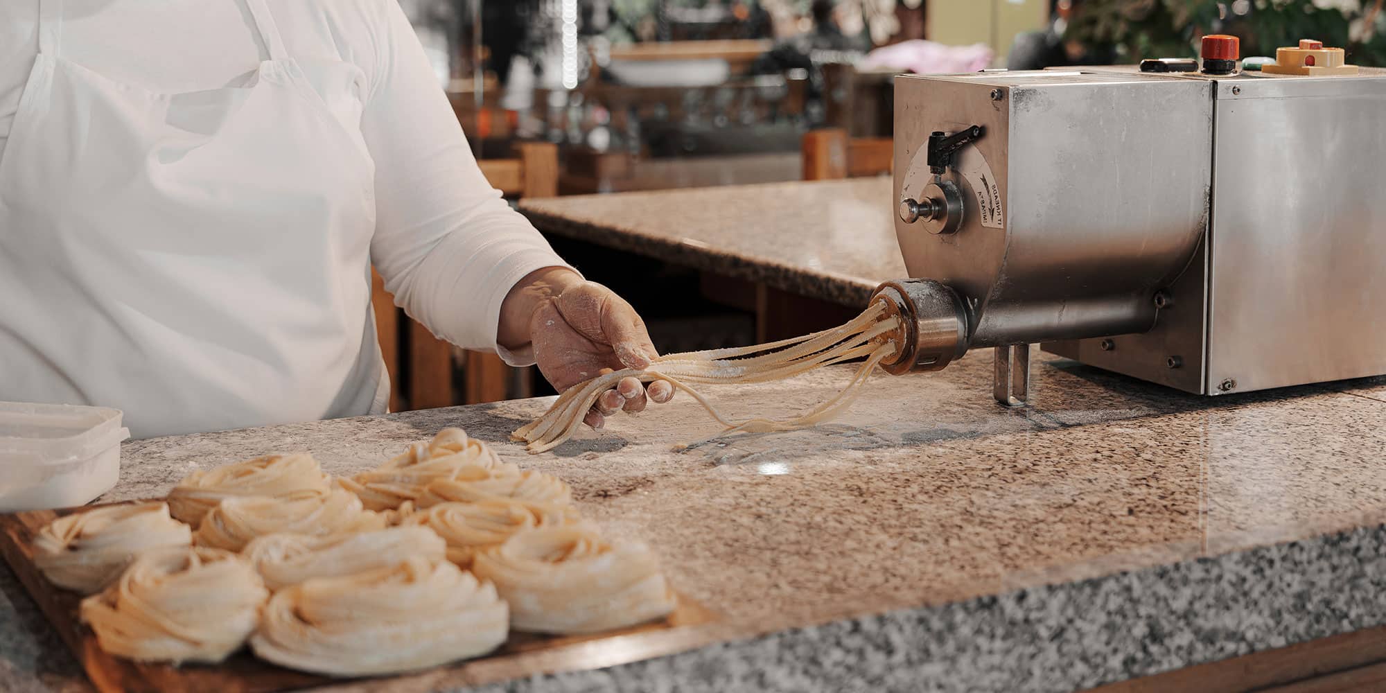 female cook rolling uncooked pasta dough